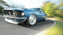 Взгляд под углом на синий Ford Mustang, входящий в крутой поворот